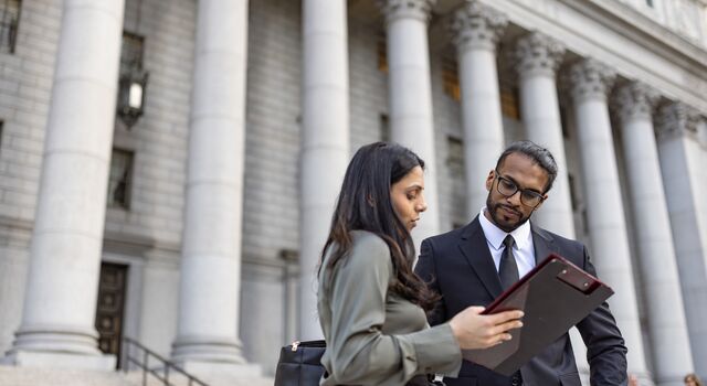 COLOUR-IMAGE_man-and-woman-looking-at-documents-in-front-of-government-building_feb26
