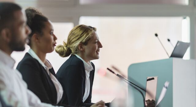 COLOUR-IMAGE_woman-smiling-in-a-government-setting-meeting_feb26
