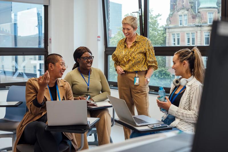 COLOUR-IMAGE_female-teacher-discussing-with-three-students_apr26