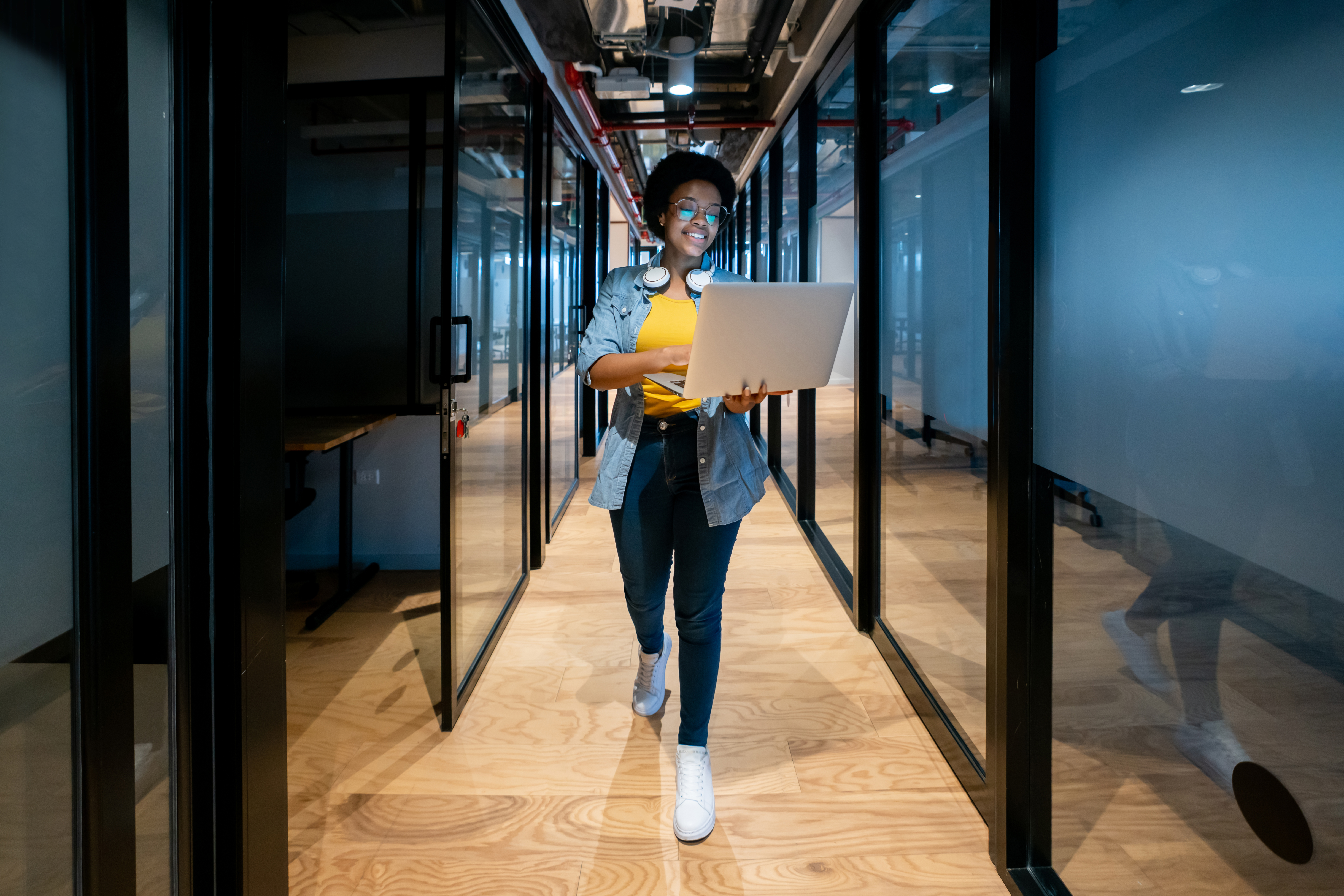 COLOUR-IMAGE_woman-laptop-device-walking-corridor-office_mar26
